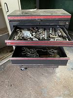 Photo of black metal tool cabinet with drawers open revealing various socket wrenches and tools inside.