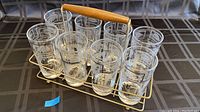 Front side view of the 12 vintage glasses in metal carrier with wooden handle