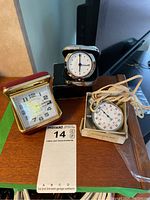 Overview of two travel clocks and one stopwatch on a wooden surface