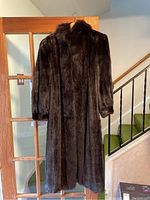 Full front view of the dark brown fur coat hanging on door, showing length and collar detail