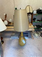 Full view of lamp showing gourd-shaped yellow glazed ceramic base and beige tapered shade.