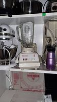 Kitchen appliances on shelf: KitchenAid mixer, Osterizer 8 blender, electric slicer, seltzer bottle