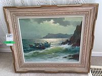 Framed painting showing two boats on the sea near rocks with waves crashing, under a cloudy sky.