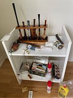 Full view of the collection on the white shelf including pipes, matchboxes, flask, and cleaning sprays