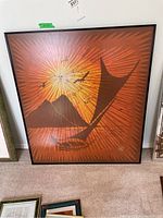 Full view of large framed print with orange sunburst background, sailboat, birds, and mountain silhouette.