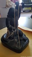 Front angle showing the Inuit figure kneeling and holding a fishing line in both hands, carved from black soapstone with visible details.