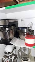 Hamilton Beach stand mixer model 63325 with metal mixing bowl, stainless steel attachments, and instruction manual sitting on a shelf.