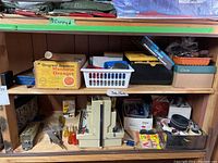 Two wooden shelves filled with assorted tools, hardware items, and small containers labeled for organization. Includes hand tools, hardware parts, and other miscellaneous items.
