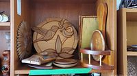 Overview of wooden decor, showing hummingbird and sun wall plates, fish carved plates, tissue box holder and wall shelf