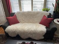 Sheepskin draped over dark gray sofa with red pillows