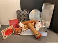 Photo showing all items in the lot: Silpat mats, metal pans, muffin tin, rolling pins, measuring cup, scrapers, hourglass timer, and vintage booklets.