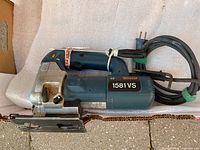 Side view of Bosch jig saw showing the body, handle, base plate, adjustment knob, and power cord wrapped and secured.