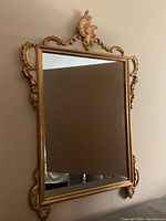 Full front view of rectangular mirror with ornate carved wood frame, gold and white finish, showing top crest and side scrollwork