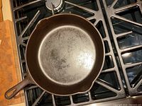 Top view of cast iron skillet on stove showing cooking surface area and handle.