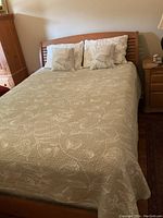 Bed made with the quilted coverlet and two decorative pillows arranged at the headboard. Shows overall appearance and colors of coverlet set in use.