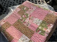 Folded view of the quilt showing patchwork floral and solid pink fabrics
