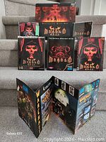 Overall view of the Diablo II Exclusive Gift Set contents including game box, strategy guide, manuals, and promotional brochures arranged on stairs.