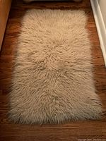 Full view of the Greek Flokati wool rug on hardwood floor showing shaggy long wool fibers and rectangular shape.