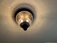 Lit flush mount ceiling light on ceiling casting radial light pattern through seeded bubble glass globe