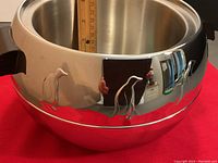 Close-up side view showing polished stainless steel body with two penguin designs and interior cavity depth measurement with ruler