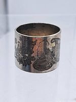 Side view of silver napkin ring showing engraved banners and Queen Victoria profile with crown and inscription 'VICTORIA'.