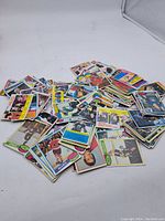 Photo showing a large pile of vintage hockey cards spread on a white surface.