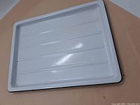 Top view of the roasting tray interior showing white enamel and multiple parallel ridges