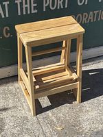 Wooden folding stool folded as a compact stool, showing slatted wooden top and base