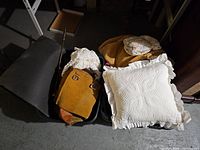 Two totes filled with assorted vintage and household items including pillows, textile pieces, and bags.