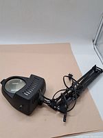 Full view of vintage mounted magnifier with adjustable arm and attached power cord.