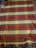Full view of the wool blanket laid out showing striped pattern in warm colors and fringed ends.