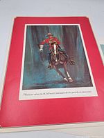 Close-up of full-colour print showing RCMP officer on horseback in traditional uniform against a dark background, bordered in red.