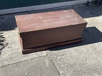 Solid wood chest exterior top view showing flat lid with brass corner protectors and visible wear.
