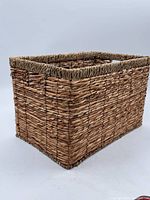 Side view of rectangular woven basket showing natural weave, fiber wrapping on rim, and side handle cut-out.