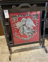 Full view of the beaded needlepoint angel mounted in the wooden frame stand showing the entire piece and its structure.