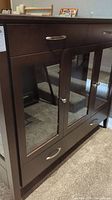 Full front view of the Woodworks display cabinet showing glass panel doors and drawer handles