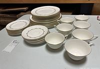 Overall view of plates and cups arranged on a table showing multiple pieces including large plates, small plates, and cups with gold accents.