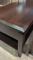 Close-up of the coffee table's beveled edge top surface, showing dark brown wood finish and thickness.