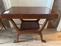 Full view of wood side table from front showing rectangular top, curved legs, and lower shelf.