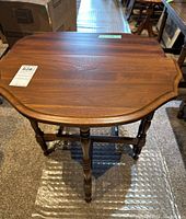 Top view of one wooden side table showing scalloped edge and wood grain finish