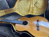 Photo showing the front of the vintage Epiphone classical guitar inside the case, displaying the wood finish and nylon strings.