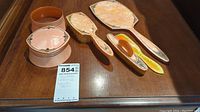 Overview of the entire five-piece vintage vanity set on wooden surface showing powder jar, hairbrush, hand mirror, comb, and handled tray.