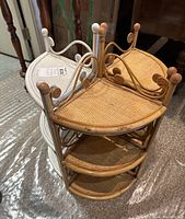 Two wicker corner shelves stacked showing front white and natural rattan color, both 3-tier with curved edge and ornate scroll detail.