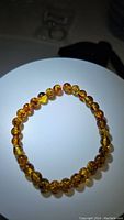 Image showing natural piebald Baltic amber beads strung on stretchy elastic forming a closed circular bracelet on a white surface under light.