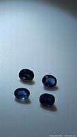 Four oval deep blue sapphires shown on white background, highlighting color and inclusions.