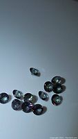 Multiple round faceted mystic topaz gemstones on white background showing iridescent colors.