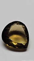 Pear-shaped natural champagne citrine gemstone photographed on plain background showing facets and color
