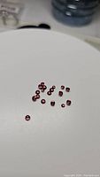 Multiple small round cabochon garnet gemstones on white surface showing color and shape