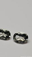 Pair of oval cut green amethyst/prasiolite stones with teal color on a plain background for clarity of gemstone shape, color, and clarity.