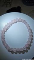 Top view of natural rose quartz stretchy bracelet showing smooth round beads with consistent pale pink color.